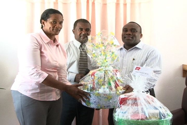 (L-R) Rams Group of Companies Representative Ms. Shirley Julius presents baby hampers to Medical Chief of Staff Dr. John Essien while Acting Hospital Administrator Mr. Johnson Morton and Matron Aldris Pemberton Dias (out of photograph) look on