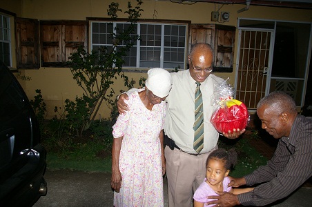 Premier of Nevis, Hon. Joseph Parry and Cabinet Secretary, Mr. Ashley Farrell giving a gift basket to Mrs. Inez Claxton and her granddaughter for her long-time support to him in recognition of his 25 years of service to Parliament